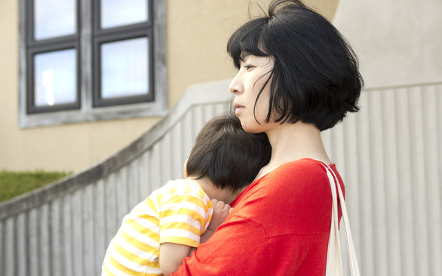 眠る子どもを抱っこする母親